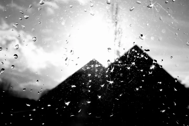 Une pyramide de verre vue à travers une vitre couverte de gouttes de pluie