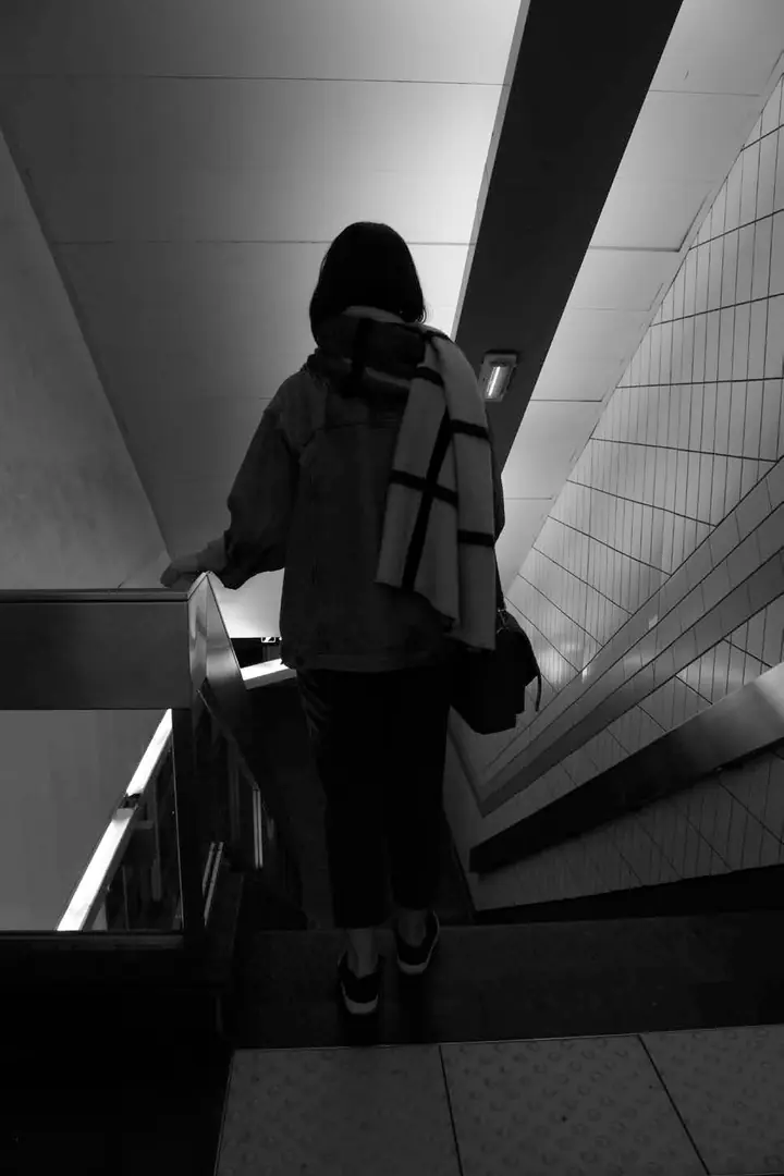Une femme de dos descend un escalier mécanique