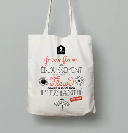 Un tote bag à la citation calligraphiée « Je vois fleurir avec éblouissement la plus petite fleur sur ce tas de fumier qu’est l’humanité », signée Abbé Pierre