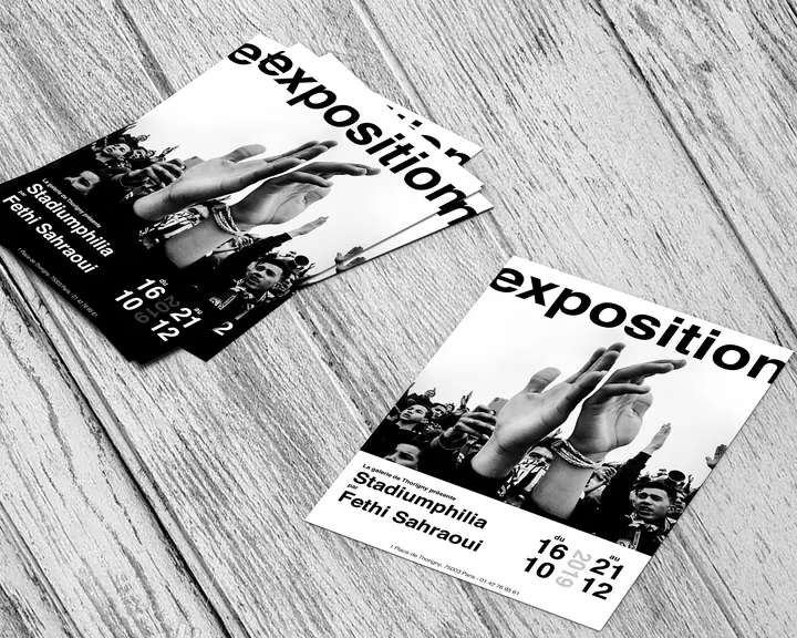 Des flyers « exposition » Stadiumphilia de Fethi Sahraoui, étalés sur un plancher
