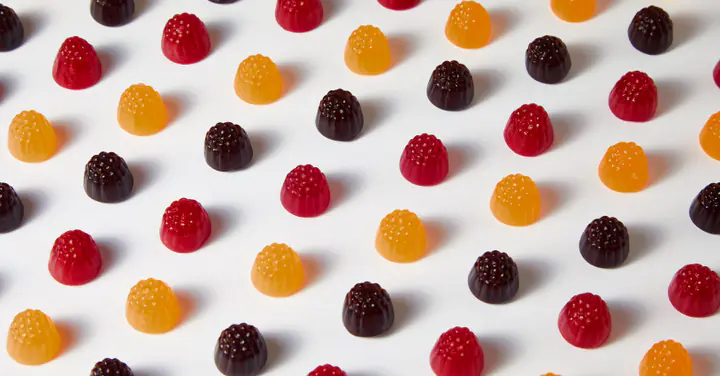 Des gommes rouges, orange et violettes alignées, en gros plan