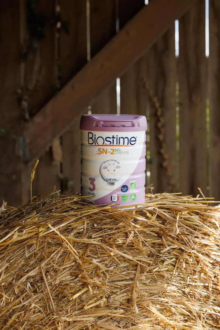 Une boîte de lait Biostime sur la paille, dans une grange