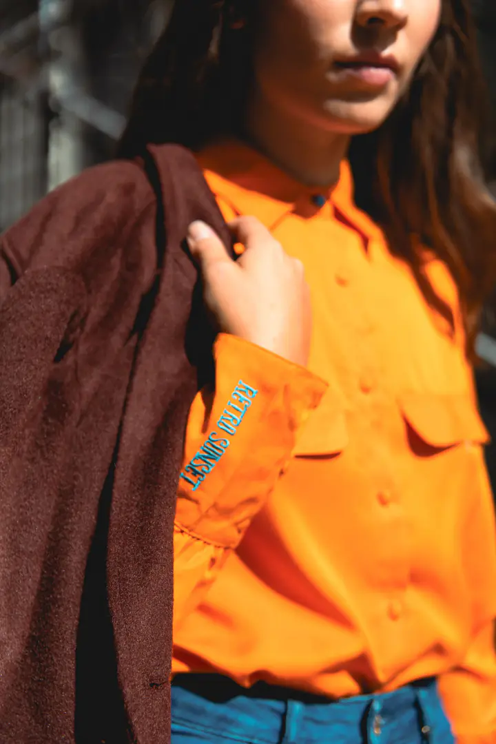 Gros plan sur une chemise orange et une veste bordeaux